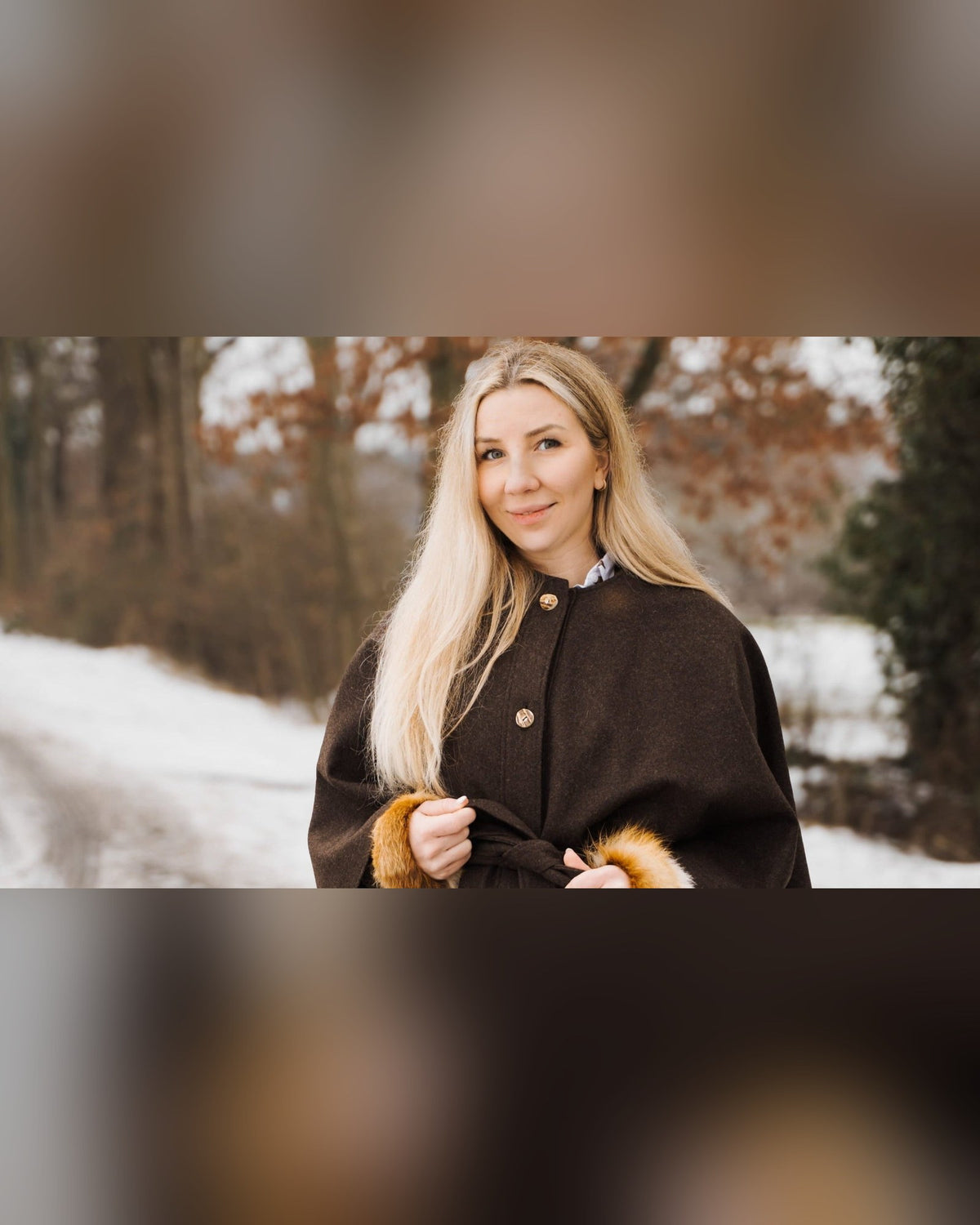 Frau mit Rotfuchs-Pulswärmern und Cape in verschneiter Landschaft