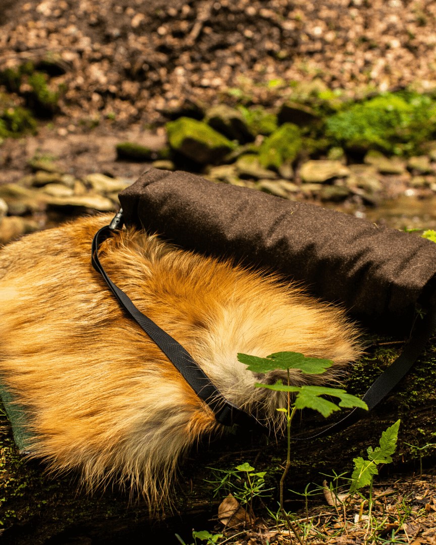 Rotfuchs Loden-Muff liegt auf Waldboden zwischen Steinen