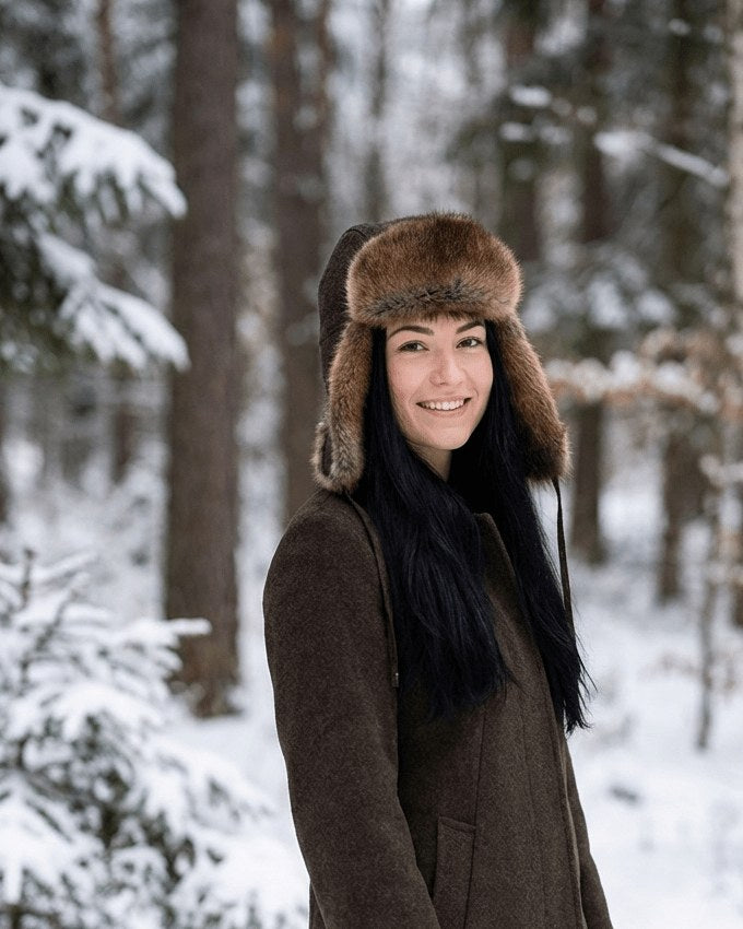 Frau mit Bisammütze im verschneiten Nadelwald