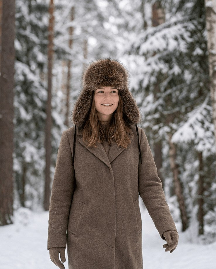 Frau mit Waschbärmütze im winterlichen Wald